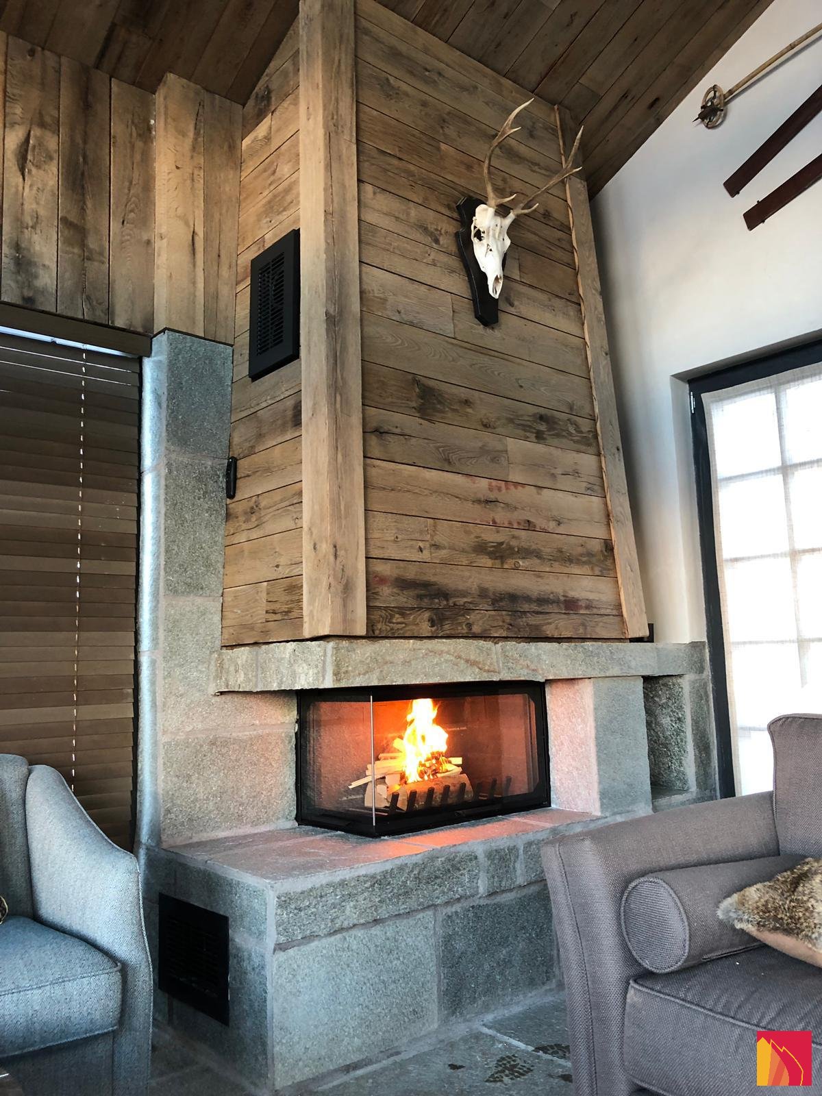 Cheminée vitre latérale avec un socle en pierre et un revêtement en bois - Carron-Lugon